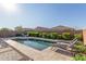 Backyard pool area is surrounded by beautiful landscaping and a stone patio with lounge chairs at 22920 E Indiana Ave, Queen Creek, AZ 85142
