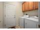 Functional laundry room equipped with a washer, dryer, and overhead cabinets for storage at 26247 W Lone Cactus Dr, Buckeye, AZ 85396