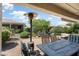 Covered patio features a brick floor, heat lamp, seating, table and chairs, and lush landscaping and greenery at 26247 W Lone Cactus Dr, Buckeye, AZ 85396