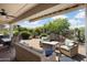 Covered patio with brick floor features a ceiling fan, outdoor seating, throw pillows and access to the landscaped yard at 26247 W Lone Cactus Dr, Buckeye, AZ 85396