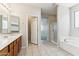 Bright bathroom featuring dual vanity, soaking tub, and shower with glass door at 3310 W Chambers St, Phoenix, AZ 85041