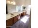 Bright bathroom featuring dual sinks, wood cabinets, a large mirror, and natural light at 4008 E Knox Rd, Phoenix, AZ 85044