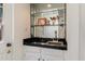 This wet bar features a black countertop, mirror backsplash, glass shelving, and white cabinets at 4015 N 78Th St # 135, Scottsdale, AZ 85251