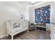 bedroom featuring a crib, chair, baby mobile and sports themed curtains at 42726 N Livingstone Way, Anthem, AZ 85086