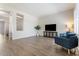 Bright living room featuring modern gray flooring, a TV, and comfortable blue armchairs at 42726 N Livingstone Way, Anthem, AZ 85086