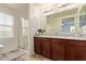 Well-lit main bathroom with double sinks, dark wood cabinets, and a walk-in shower at 4807 W St Anne Ave, Laveen, AZ 85339