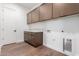 This laundry room features upper and lower cabinet storage, clean white walls, and durable laminate wood flooring at 5744 E Lowden Rd, Cave Creek, AZ 85331