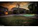 Beautiful backyard with a green lawn, pool, and outdoor fireplace at sunset at 7156 S Forest Ave, Gilbert, AZ 85298