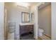 Bright bathroom with a wooden vanity, a large mirror, and a toilet in a separate alcove at 7227 E Northridge St, Mesa, AZ 85207