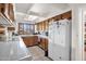 Functional kitchen with wood cabinets, tile countertops, white appliances, and a well-lit area at 1040 E Clinton St, Phoenix, AZ 85020
