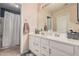 Bright bathroom featuring dual sinks with white cabinetry, a large mirror, and shower at 10852 E Contessa St, Mesa, AZ 85207