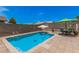 Refreshing pool with sun umbrella, table, and chairs creating an inviting outdoor space at 10852 E Contessa St, Mesa, AZ 85207