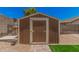 Exterior view of a home's wooden backyard shed with a brick pathway and adjacent wall at 10852 E Contessa St, Mesa, AZ 85207