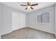 Bright bedroom featuring wood floors, a ceiling fan, sliding closet doors and a window at 10943 W Alice Ave, Peoria, AZ 85345