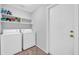 Functional laundry room with washer, dryer, storage shelves, and access to the exterior at 10943 W Alice Ave, Peoria, AZ 85345