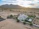 Desert property with a large home, pool, green lawn, circular drive and a backdrop of distant mountains at 11250 W Prospector Dr, Queen Creek, AZ 85144