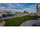 Beautiful backyard featuring a sparkling pool with water feature, fire pit, outdoor seating, and green artificial grass at 11250 W Prospector Dr, Queen Creek, AZ 85144