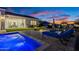Stunning backyard with pool, outdoor seating, and outdoor kitchen with view of the home at twilight at 11250 W Prospector Dr, Queen Creek, AZ 85144