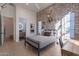Inviting bedroom with exposed brick accent wall, stylish decor, and a view into an ensuite bathroom at 11250 W Prospector Dr, Queen Creek, AZ 85144