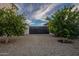 Gated driveway with black gate, lush trees, and serene landscaping, enhancing curb appeal and privacy at 11250 W Prospector Dr, Queen Creek, AZ 85144