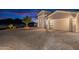 Three-car garage with brick driveway and desert landscaping at dusk at 11250 W Prospector Dr, Queen Creek, AZ 85144