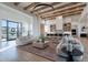 A modern living room is full of light with hardwood floors, beamed ceilings, and oversized windows at 11250 W Prospector Dr, Queen Creek, AZ 85144