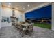 Inviting outdoor kitchen and dining area with built in grill and view of the landscaped backyard at twilight at 11250 W Prospector Dr, Queen Creek, AZ 85144