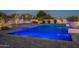 Stunning blue-lit pool and spa with tiled accents, surrounded by lush landscaping and privacy walls at 11250 W Prospector Dr, Queen Creek, AZ 85144