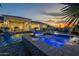 Backyard pool with a spa, water feature and beautiful landscaping at twilight at 11250 W Prospector Dr, Queen Creek, AZ 85144