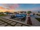 Stunning backyard at dusk featuring a pool with fountain, lounge seating, a fire pit, and manicured landscaping at 11250 W Prospector Dr, Queen Creek, AZ 85144