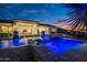 Beautiful backyard with an illuminated pool, water features, and a covered patio, perfect for entertaining at 11250 W Prospector Dr, Queen Creek, AZ 85144