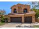 Beautiful two-story home with arched windows, tile roof, three car garage, and mature landscaping at 1211 E Desert Flower Ln, Phoenix, AZ 85048