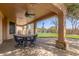 Covered patio features ceiling fan, brick floor, outdoor table set, view of the pool and backyard at 1211 E Desert Flower Ln, Phoenix, AZ 85048