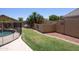 Serene backyard with a cozy swing, lush green lawn, and decorative stone wall accents by the pool at 12933 W Monterey Way, Avondale, AZ 85392