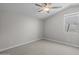 A simple bedroom has neutral carpet, baseboards, ceiling fan, and a window at 15634 W Georgia Dr, Surprise, AZ 85379