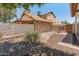 The backyard features a rock riverbed design, complemented by desert landscaping and a block fence for privacy at 1606 N Apache Dr, Chandler, AZ 85244