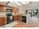 Kitchen with black appliances, wood cabinets, and a pass-through to living area at 1606 N Apache Dr, Chandler, AZ 85244