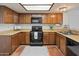 Kitchen with black appliances, wood cabinets, and tile flooring at 1606 N Apache Dr, Chandler, AZ 85244