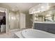 A bright bathroom featuring a soaking tub, glass enclosed shower, and large mirrors above the vanity at 18402 E Oak Hill Ln, Queen Creek, AZ 85142