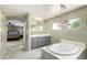 Bright bathroom featuring a soaking tub, tiled floors, and gray vanity at 18402 E Oak Hill Ln, Queen Creek, AZ 85142