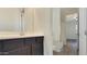 Modern bathroom vanity featuring dark cabinets and a view into the adjacent room with tub and toilet at 18617 W Williams St, Goodyear, AZ 85338