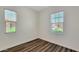 Bright bedroom featuring wood-look floors and two windows offering views of the home's exterior at 18617 W Williams St, Goodyear, AZ 85338