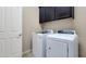 A bright laundry room with a washer and dryer and overhead cabinets at 18617 W Williams St, Goodyear, AZ 85338
