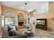 Spacious living room with travertine floors, fireplace, ceiling fan, and large windows offering plenty of light at 19275 N 88Th Way, Scottsdale, AZ 85255