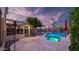 Backyard featuring a pool, hot tub, outdoor kitchen, pergola, and covered patio illuminated at dusk, ideal for evening enjoyment at 28021 N 23Rd Dr, Phoenix, AZ 85085