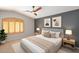 Stylish bedroom featuring a ceiling fan, modern artwork, neutral decor, and light-filled window with wooden shutters at 28021 N 23Rd Dr, Phoenix, AZ 85085