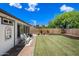 Expansive backyard features lush lawn, brick accents, and a charming seating area, perfect for outdoor living at 4252 E Zia St, Phoenix, AZ 85044