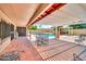 Covered patio area with tile flooring and a pergola overlooking a pool and backyard at 5140 N 69Th Ave, Glendale, AZ 85303
