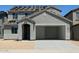 A two-story gray home with an open garage and a desert-style landscape offering modern living at 5439 S 251St Dr, Buckeye, AZ 85326