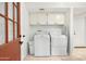 Bright laundry room with washer, dryer, white cabinets and a door to outside, providing convenience and functionality at 6043 E Hearn Rd, Scottsdale, AZ 85254